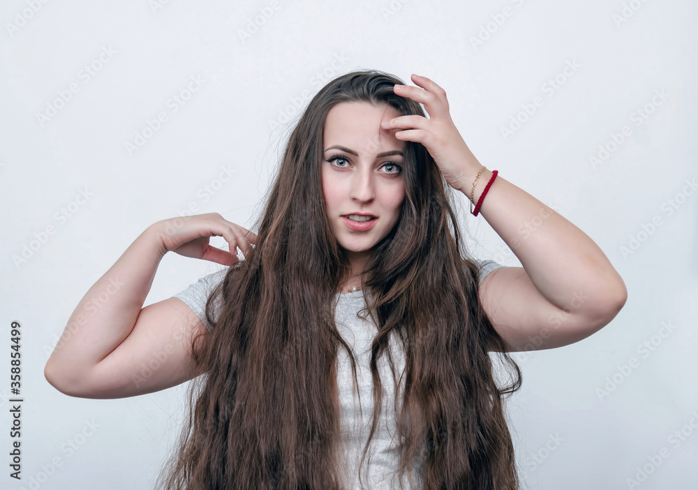 Naklejka premium Portrait of a girl with long dark hair on a white background looking at the camera. Light surprise.