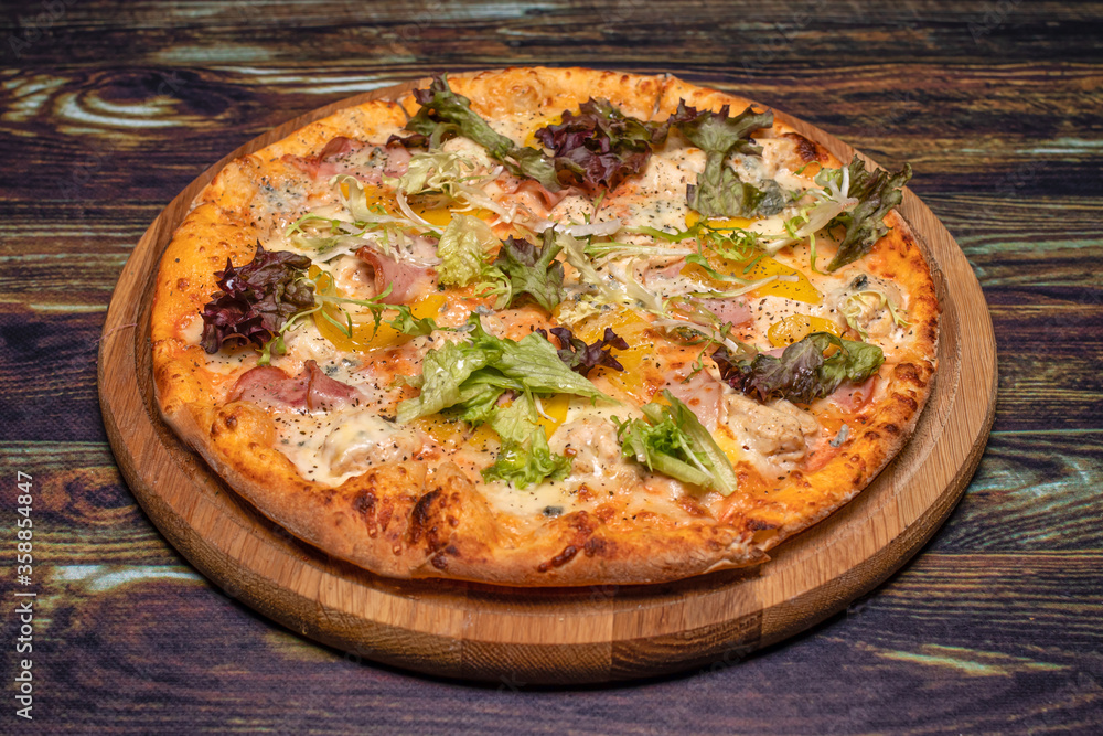 Pizza with meat, cheese, pepper and herbs on a wooden background. Italian national cuisine, delicious pastries in the restaurant.