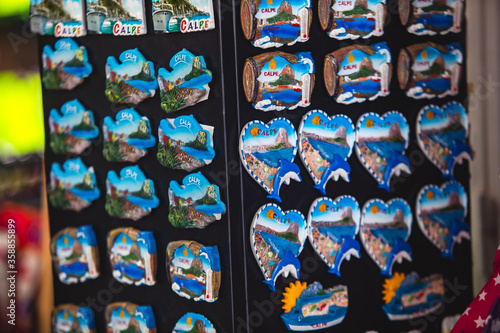 View of traditional tourist souvenirs and gifts from Calpe, Calp, Alicante, Valencia with toys, fridge magnets with and key ring keychain, in local vendor souvenir shop