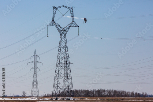 Powered cart carrying linemen on high voltage transmission line. photo