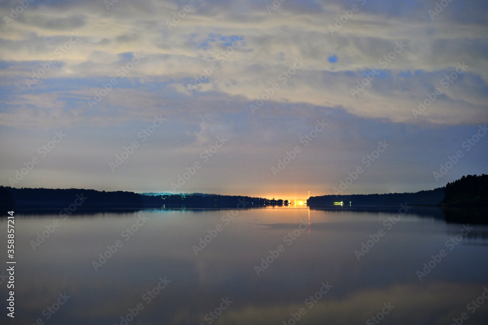 landscape with bright clouds and with reflections in the river before dawn