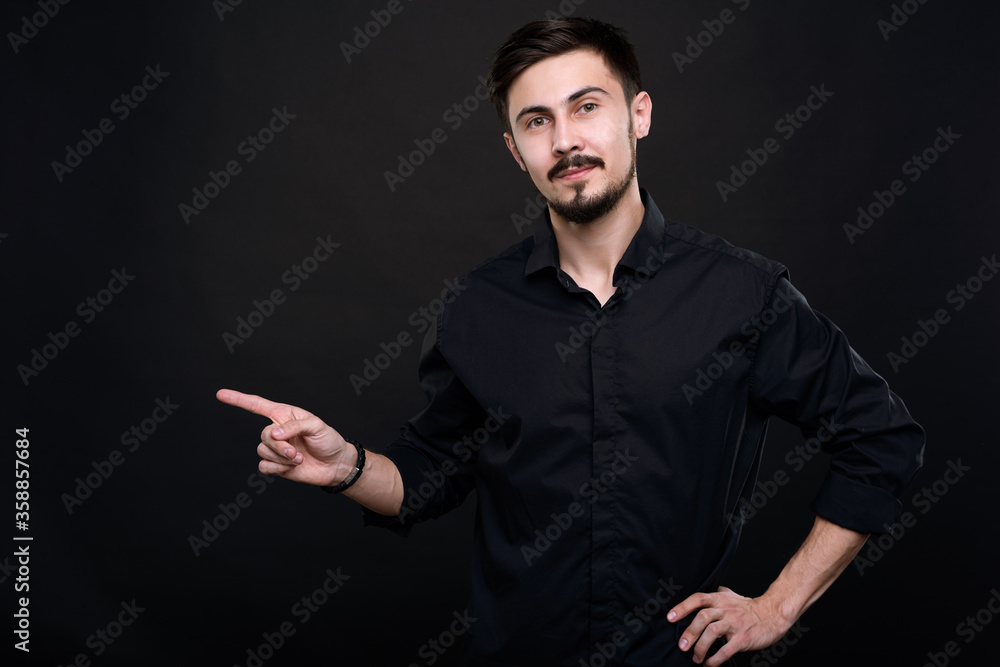 Portrait of confident sales manager with mustache and beard pointing with finger aside while recommending product