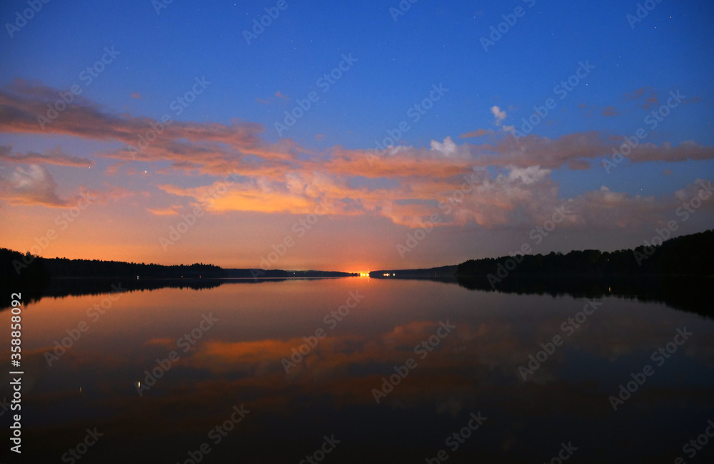 landscape with bright clouds and with reflections in the river before dawn