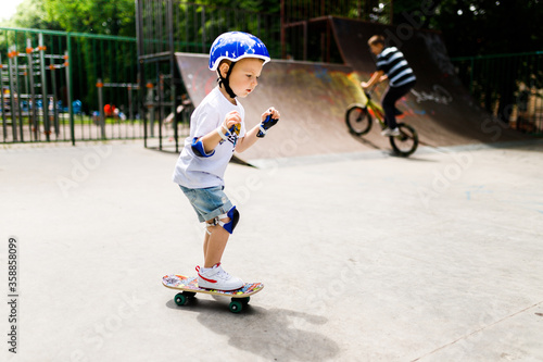 Boy with a skate in a skate park. The boy learns to skate, in full protection.