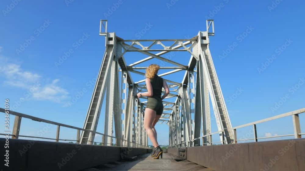 Sexy woman dancing on the railway bridge. Beautiful young dancer seductively dances and moves her buttocks. Girl dancing kizomba. Sexy woman dancing on the railway bridge. Beautiful young dancer seductively dances and moves her buttocks. Girl dancing kizomba.