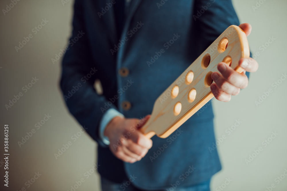 Headmaster with wooden paddle. Strict man teacher with wooden paddle with holes. School discipline and corporal punishment concept. Spanking in school.