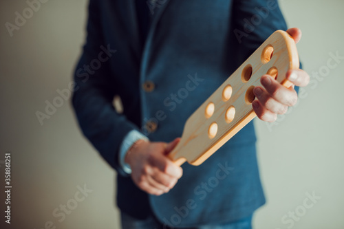 Headmaster with wooden paddle. Strict man teacher with wooden paddle with holes. School discipline and corporal punishment concept. Spanking in school.