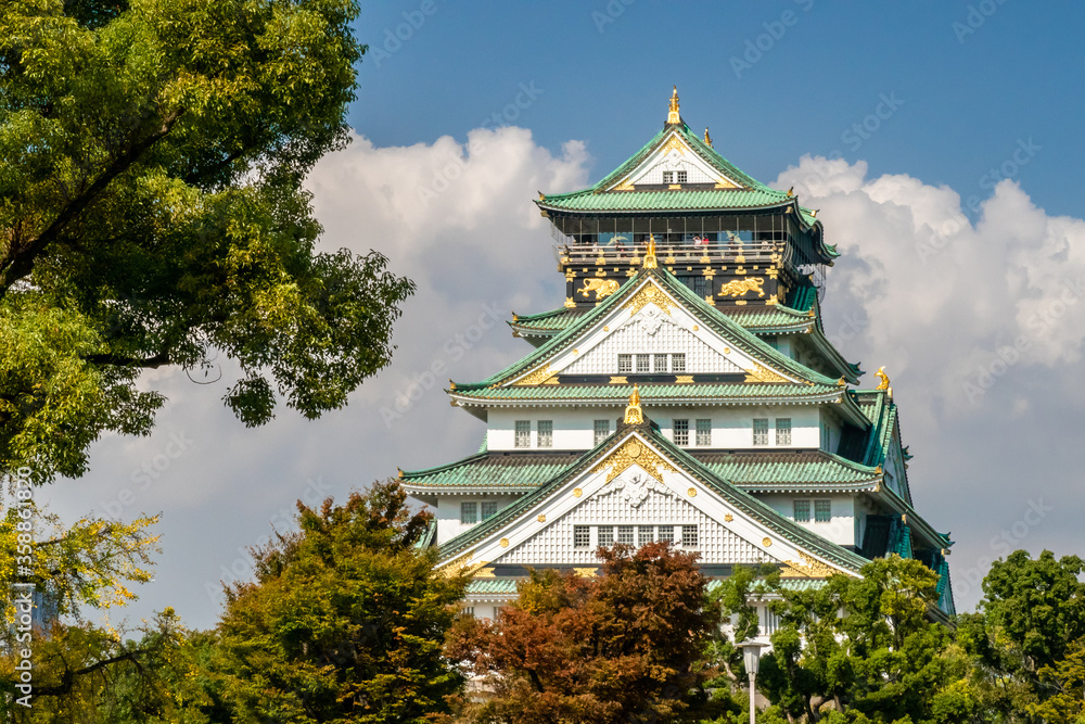 Majestic Osaka Castle view with green roof among colorful autumn trees, Japan Majestic Osaka Castle view with green roof among colorful autumn trees, Japan