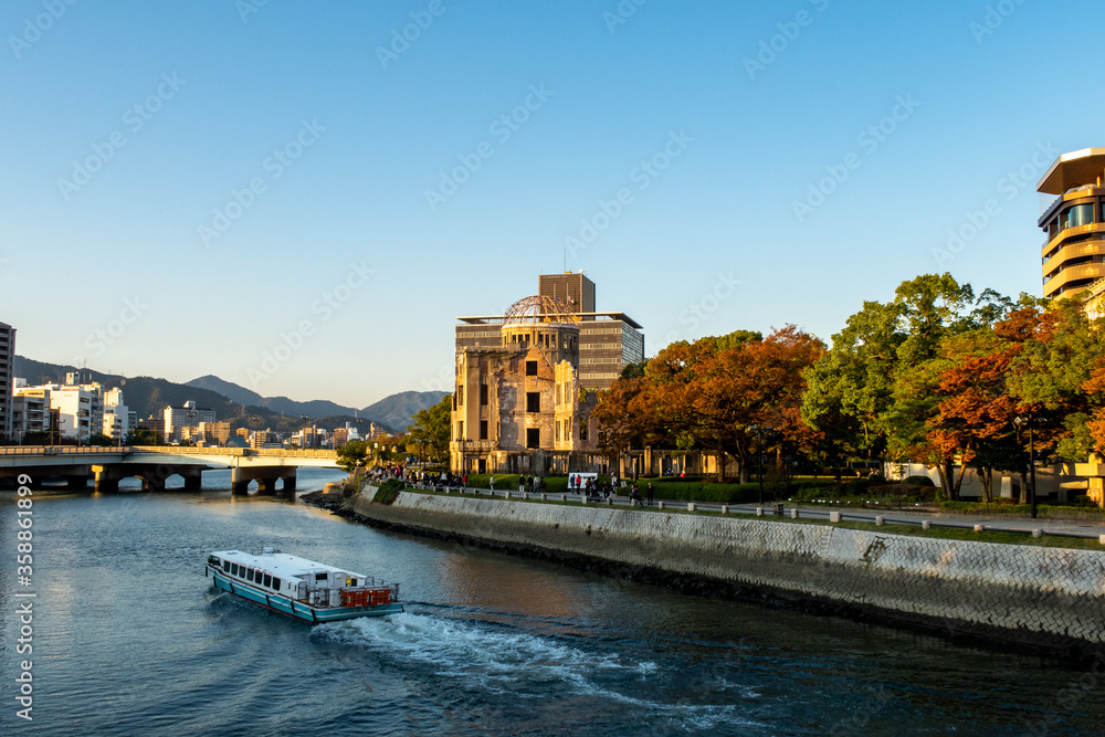 Hiroshima landscape with the view of The Hiroshima Peace Memorial (Atomic Bomb Dome),  Motoyasu River and a boat during sunset in Hiroshima, Japan.