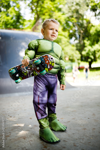 Boy with a skate in a skate park. In a superhero costume.