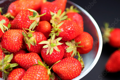 Fresh organic strawberries in a glass bowl  on a black table.