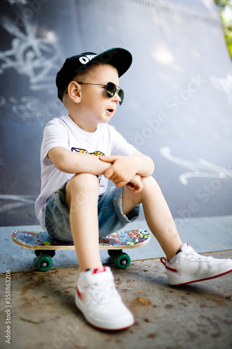 Boy with a skate in a skate park. The boy is sitting on a skateboard.