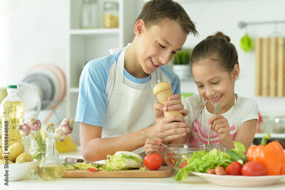 Portrait of cute brother and sister cooking together in kitchen