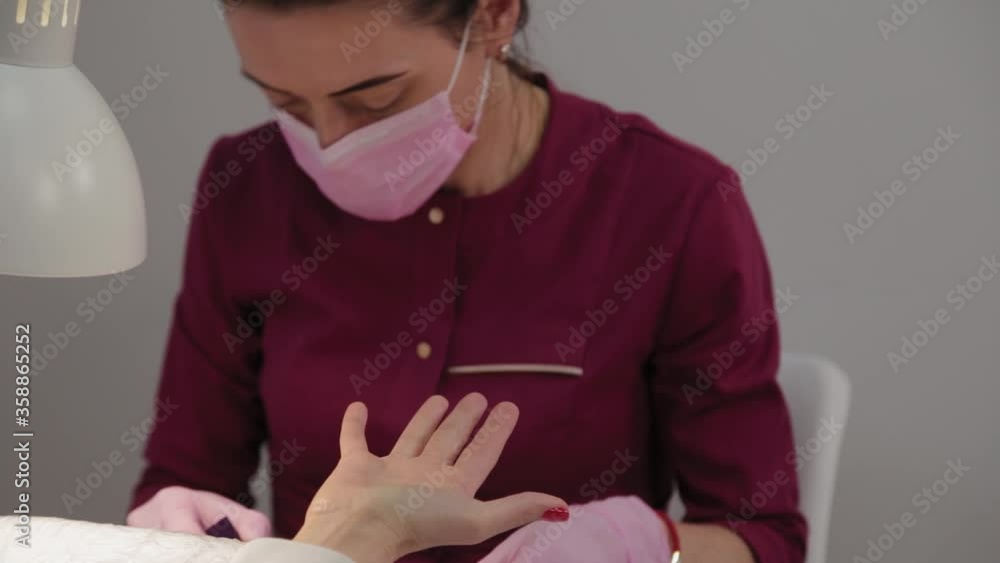 Manicurist polishes nails with a client in a beauty salon.