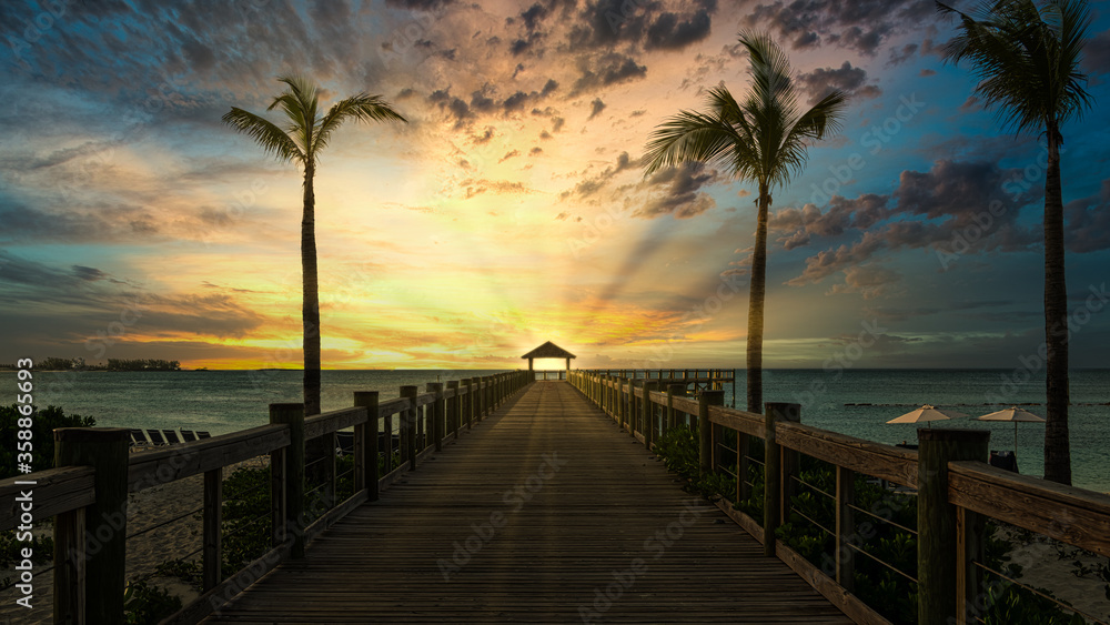 Fototapeta premium beautiful sunset at the wooden jetty at the beach with palms. 