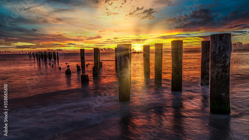 Perspective view of a wooden pier on the pond at sunset with perfectly specular reflection