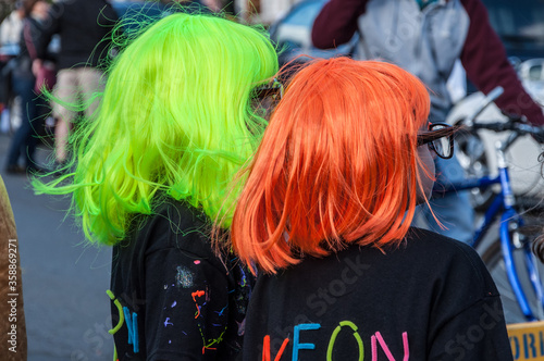 Two young girls wearing bright orange and green neon wigs at Halloween