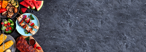 Panel kuchenny z motywem BBQ or summer picnic food side border over a dark stone banner background. Grilled meats, vegetables, fruit and salad. Top view with copy space.