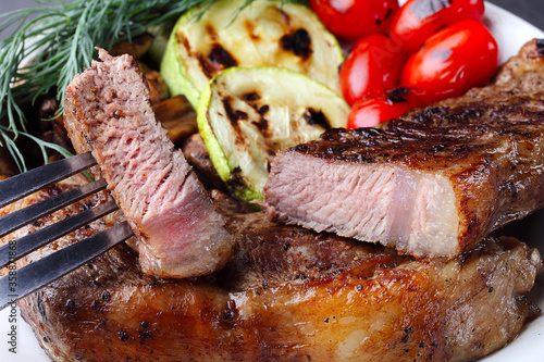 Marbled beef steak with a slice, on a plate with vegetables, selective focus, close-up