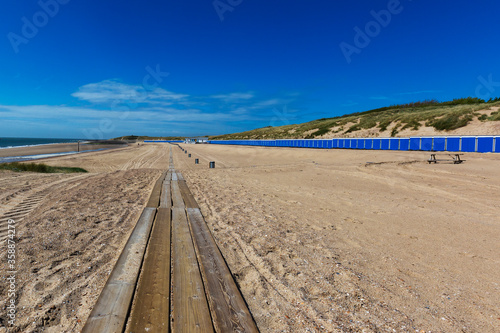 Vlissingen - beautiful sandy beach with colorful houses in a row. In the middle of the path of wooden planks. Sunny  quiet  relaxing place in the bay.