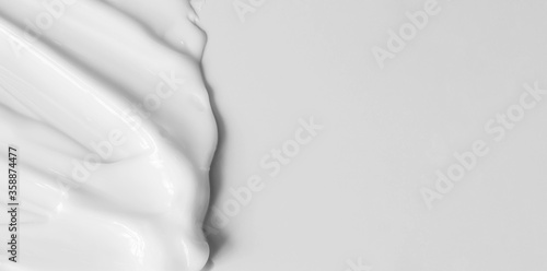 Fototapeta Close-up cream moisturiser smear smudge wavy texture on white background with copy space horizontal banner format