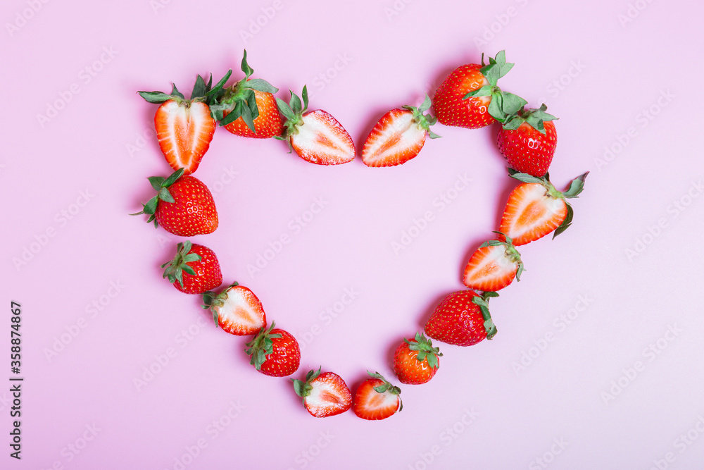 Obraz premium Frame in the shape of a heart made from ripe strawberries on a lilac background. Love concept. Valentine's day concept. Beautiful background for the designer. border, flat lay, copy space.