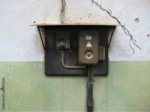 an old rusty electrical panel on a scuffed building wall