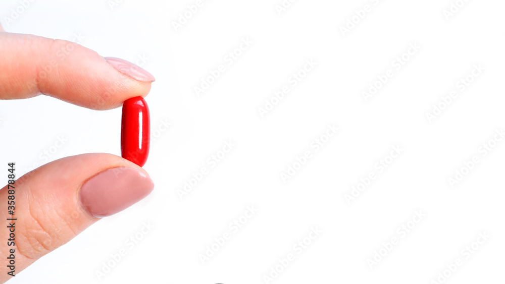 Female hand holding red tablet with two fingers close-up isolated on a white background,and place for text Female hand holding red tablet with two fingers close-up isolated on a white background,and place for text