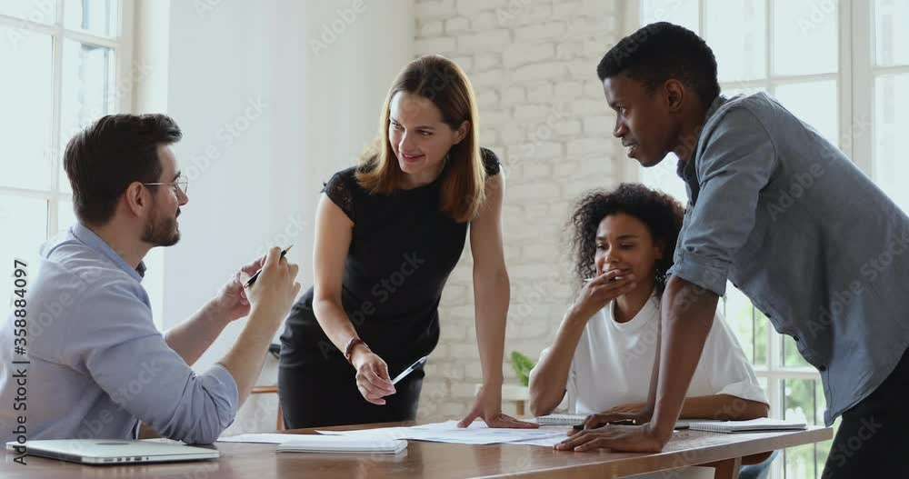 Happy female manager executive and multiracial team people analyze paperwork talking laughing working together share ideas in teamwork discuss project plan at office table at group corporate meeting