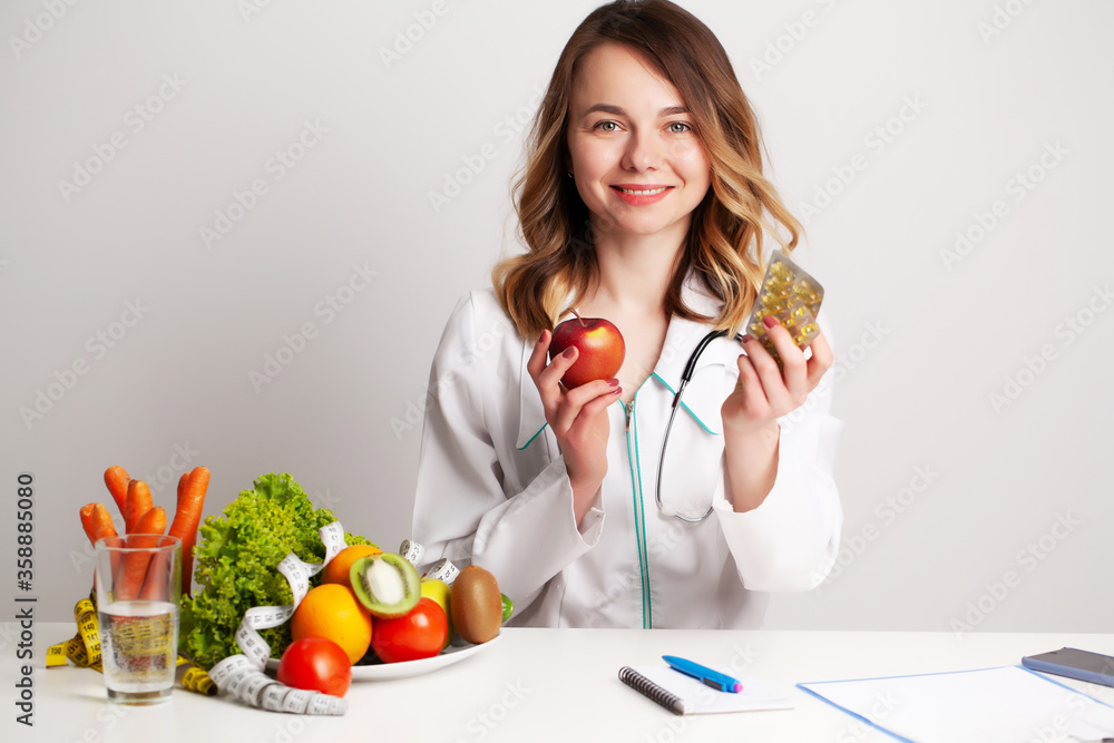 Nutritionist holding omega-3 fish oil vitamin tablet and fresh fruit in her room recording a video blog on her phone Nutritionist holding omega-3 fish oil vitamin tablet and fresh fruit in her room recording a video blog on her phone