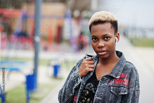 Young millennial african american girl in city. Happy black woman with wireless earphones. Generation Z concept.