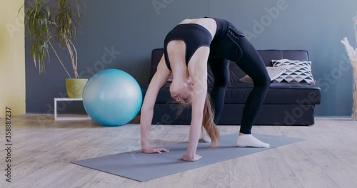 Young woman standing in bridge pose, practicing yoga photo