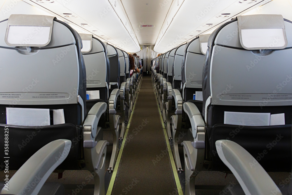 Long aisle with rows of seats and passengers in an airplane cabin (salon)