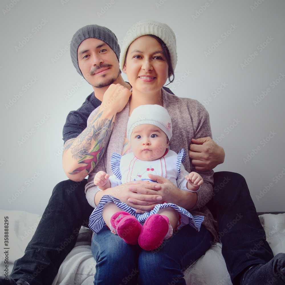 Padres jóvenes con su pequeño bebé vistiendo gorros. Retrato de padres jóvenes y su pequeña hija. Familia de padres jóvenes. Padres jóvenes con su pequeño bebé vistiendo gorros. Retrato de padres jóvenes y su pequeña hija. Familia de padres jóvenes.