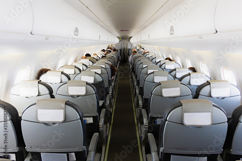 Long aisle with rows of seats and passengers in an airplane cabin (salon)