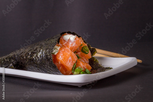 Salmon temaki sushi on white plate in black background