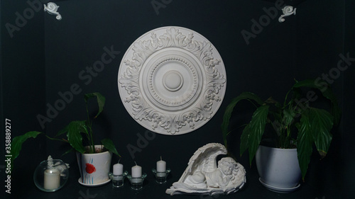 Gypsum alabaster round classical wall decoration rosette, some candles, plants and sculpture of angel.