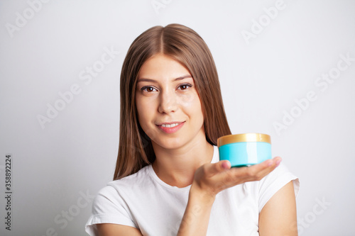 Young woman holding a jar of skin care cream