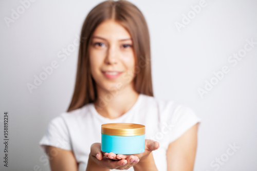 Young woman holding a jar of skin care cream