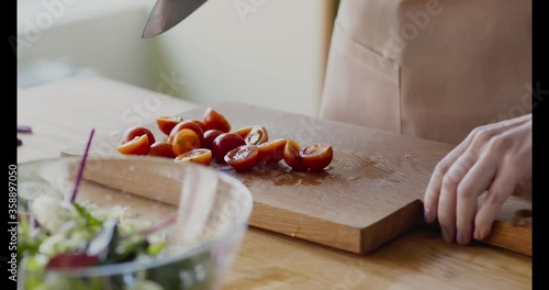 Woman cutting and adding cherry tomatoes into salad