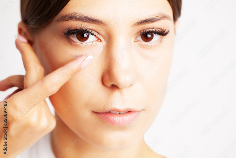 Pretty young woman puts on contact lenses for eyesight