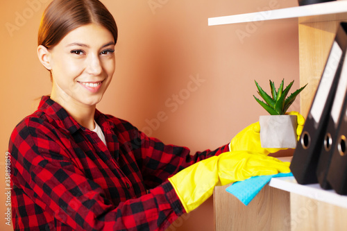 An employee of a cleaning company wipes the dust on the plants.