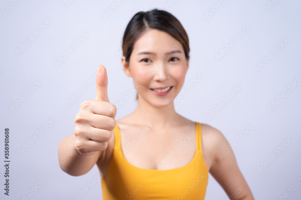 Portrait of Asian sporty woman giving thumb up isolated on white background. concept of healthy lifestyle Portrait of Asian sporty woman giving thumb up isolated on white background. concept of healthy lifestyle