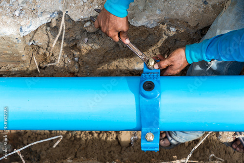Man using a large wrench on water pipes. Construction site with new Water Pipes in the ground. Sewer pipes to repair or restore in street city.