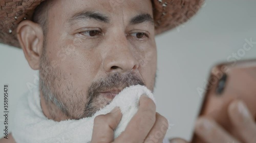 Man mustache straw hat  in mid 35-45   in the mood hopeless despair Close up  his face and hand  read bad news from smartphone Shook his head
alone in a white room .
