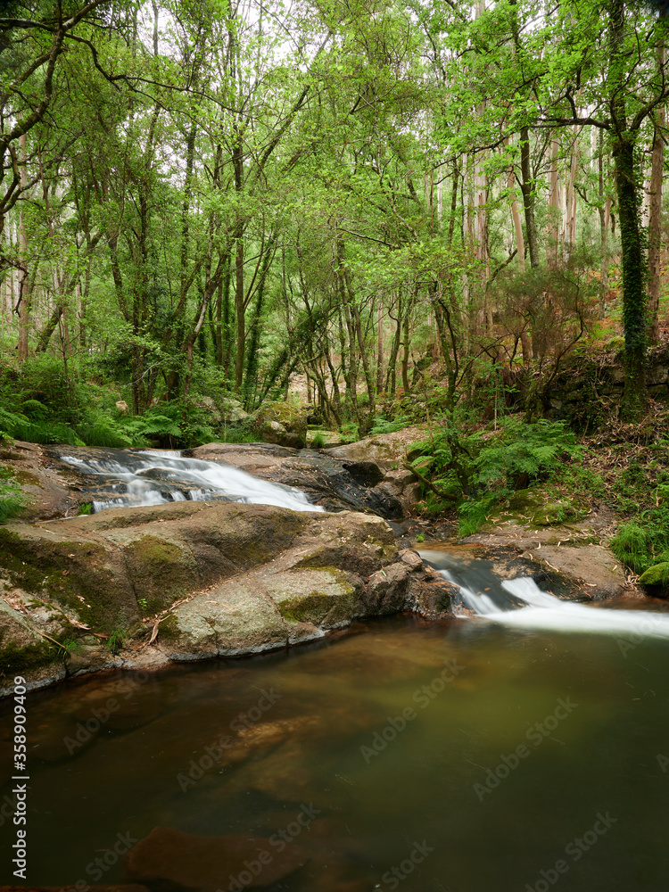 River Leça Waterfalls in Monte Cordova, Portugal. The river water runs down the big rocks of the mountain, under the green canopy of the trees in the spring River Leça Waterfalls in Monte Cordova, Portugal. The river water runs down the big rocks of the mountain, under the green canopy of the trees in the spring