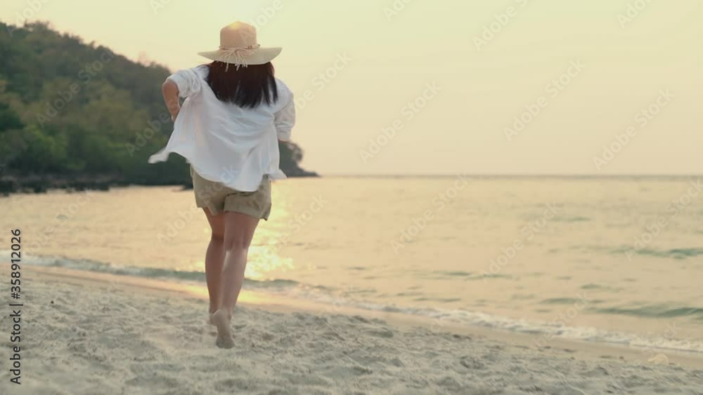 Happy asian woman traveler running into the beach with arms raised amazing beautiful ocean sand view sunset. Happy asian woman traveler running into the beach with arms raised amazing beautiful ocean sand view sunset.