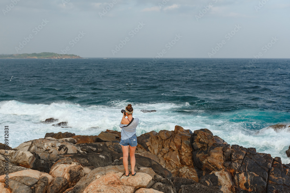 Happy young torist woman  with camera taking pictures of the sea, sunset, evening, nature