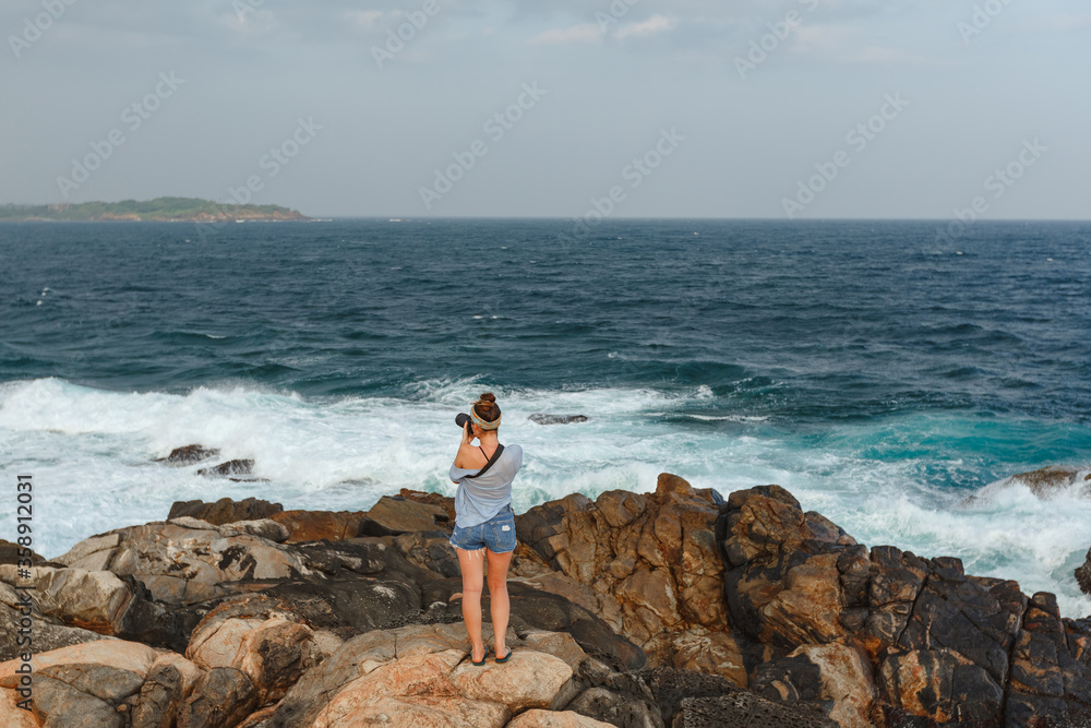 Happy young torist woman with camera taking pictures of the sea, sunset, evening, nature Happy young torist woman with camera taking pictures of the sea, sunset, evening, nature