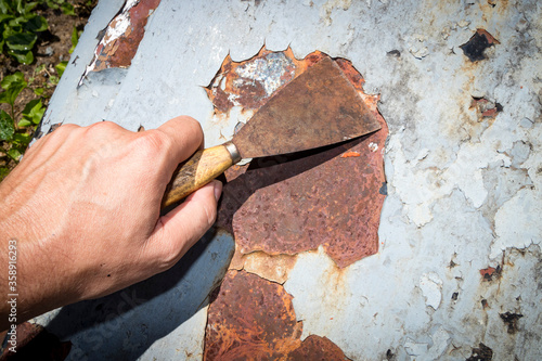 Photography Man's hand removing paint and rust damage from metal doors using a metal paint s
